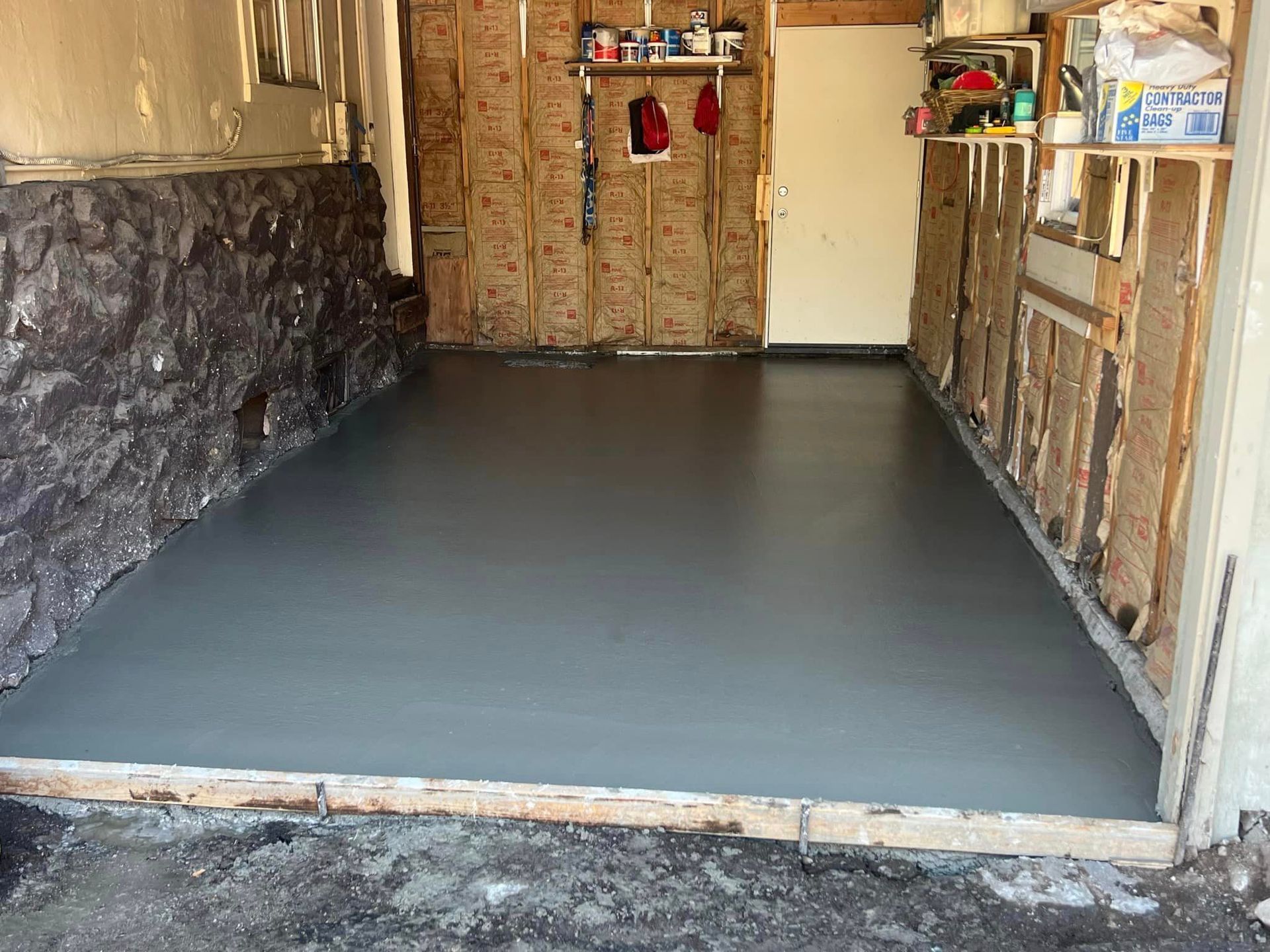 A garage with a concrete floor and a stone wall.