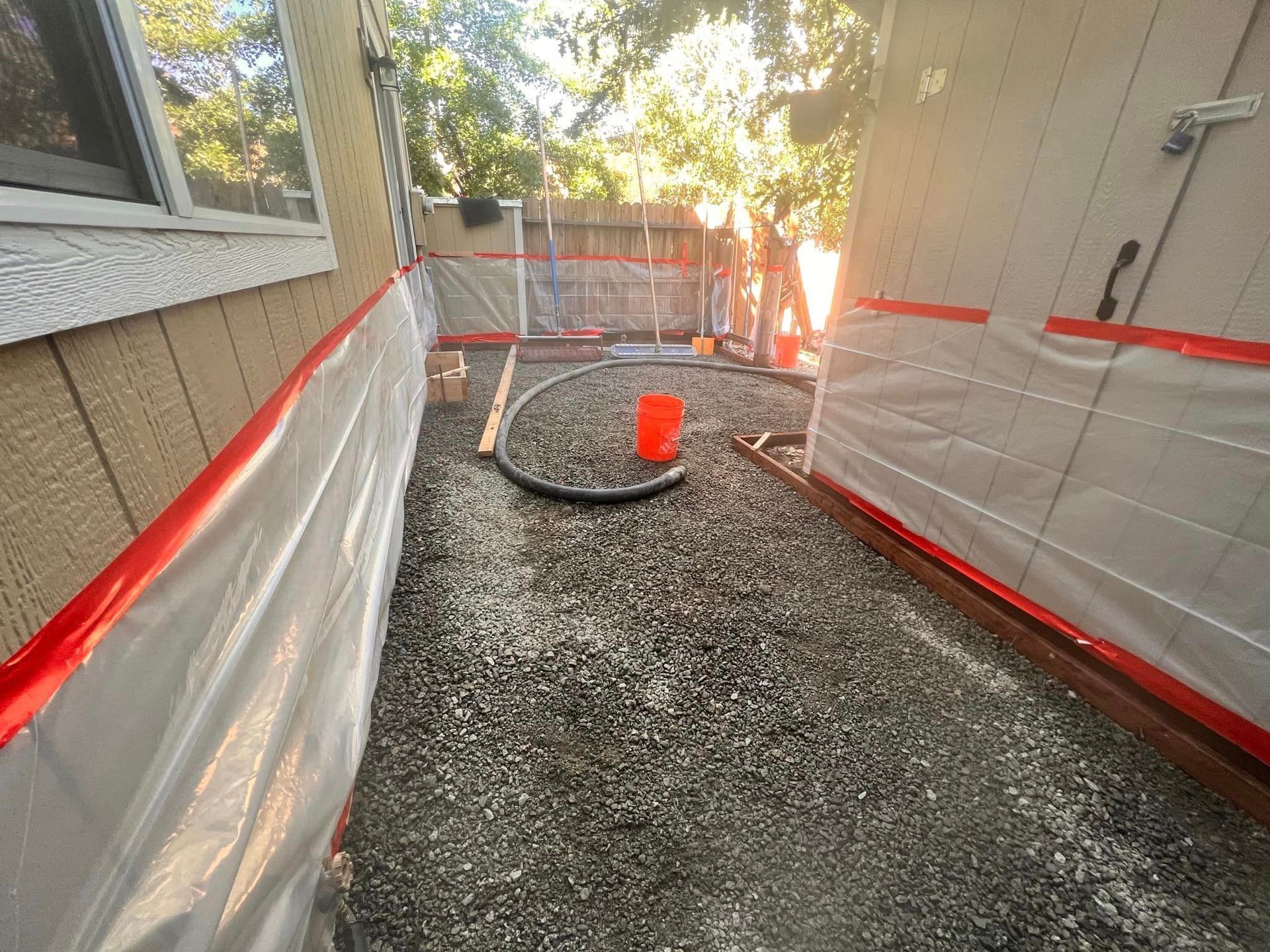 A hose is connected to a bucket on the ground in front of a house.
