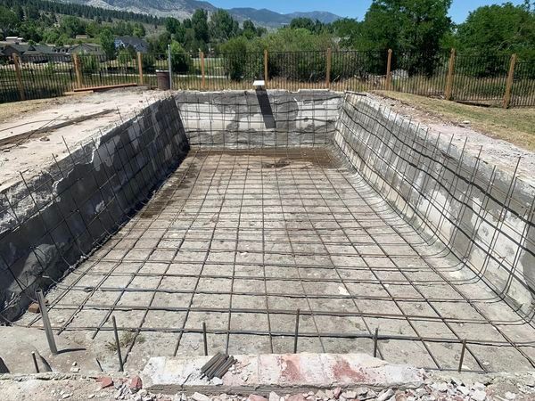 A swimming pool is being built in a yard with a fence around it.