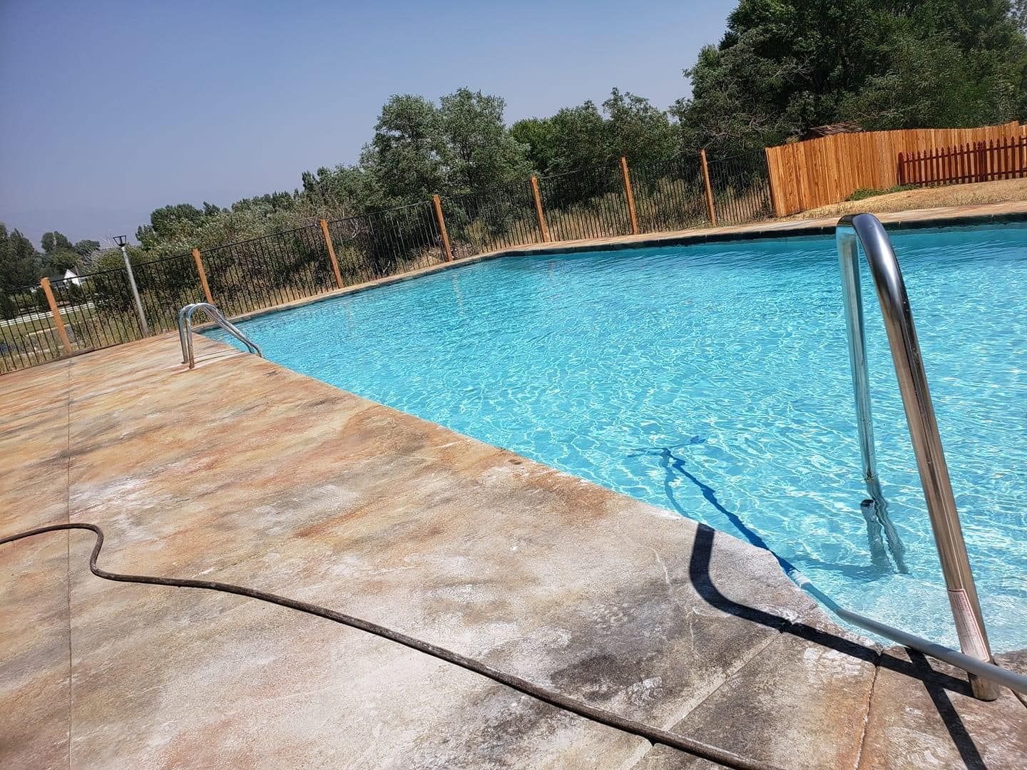 A large swimming pool with a wooden fence around it