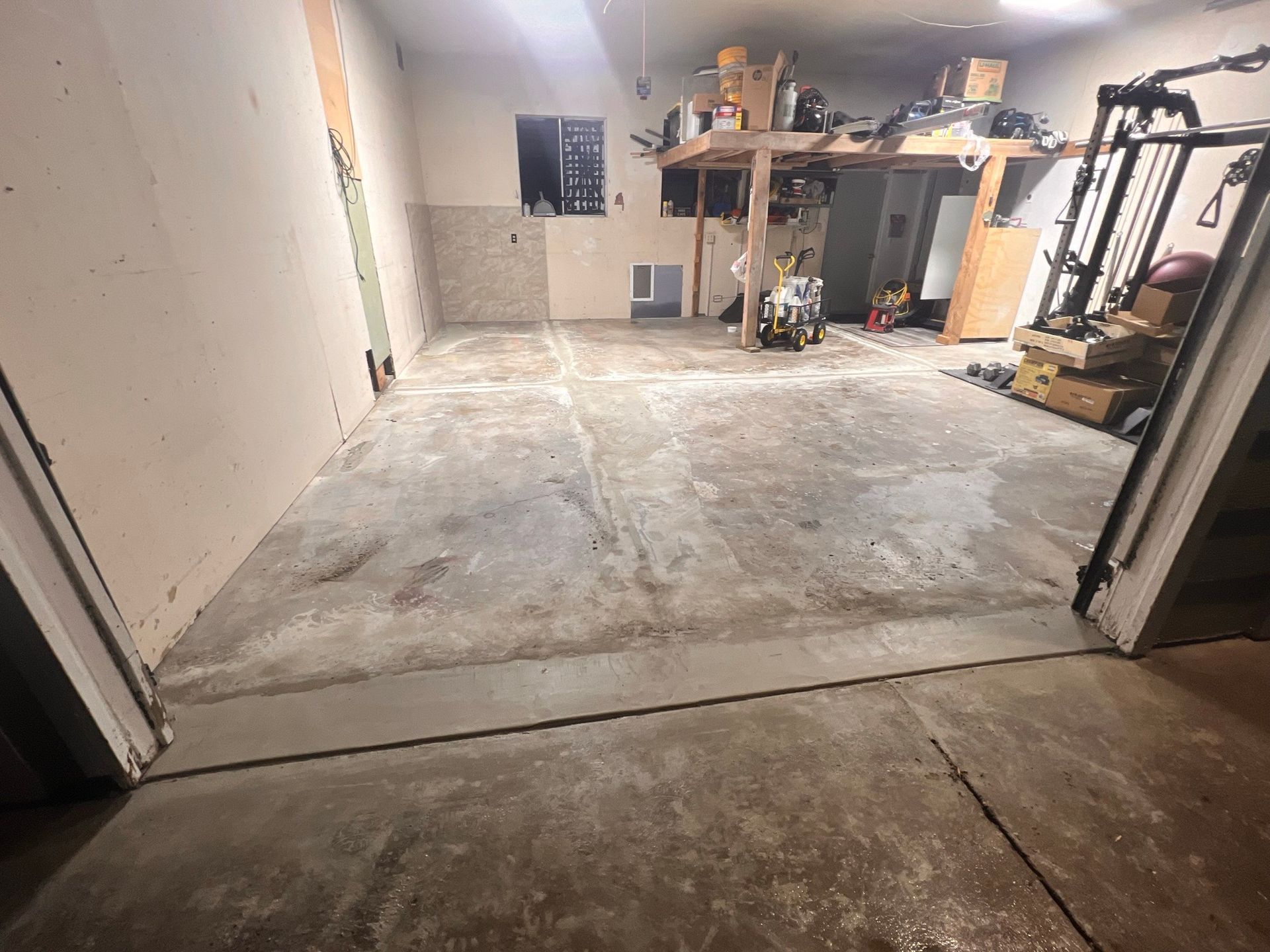 A garage with a concrete floor and a lot of junk in it.