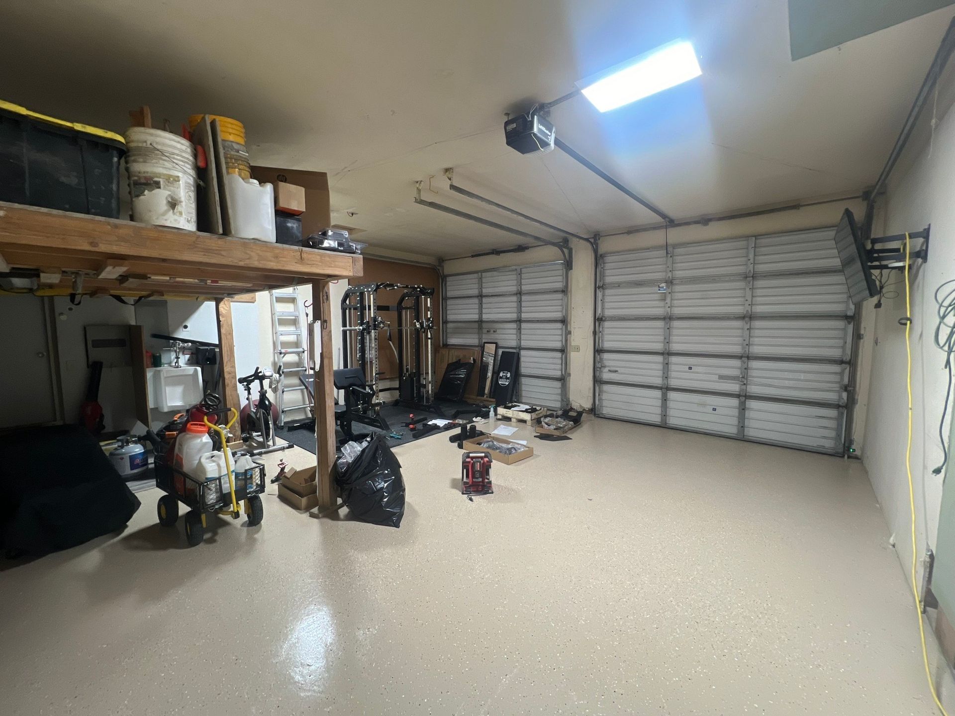 A garage with a garage door open and a lot of stuff in it.