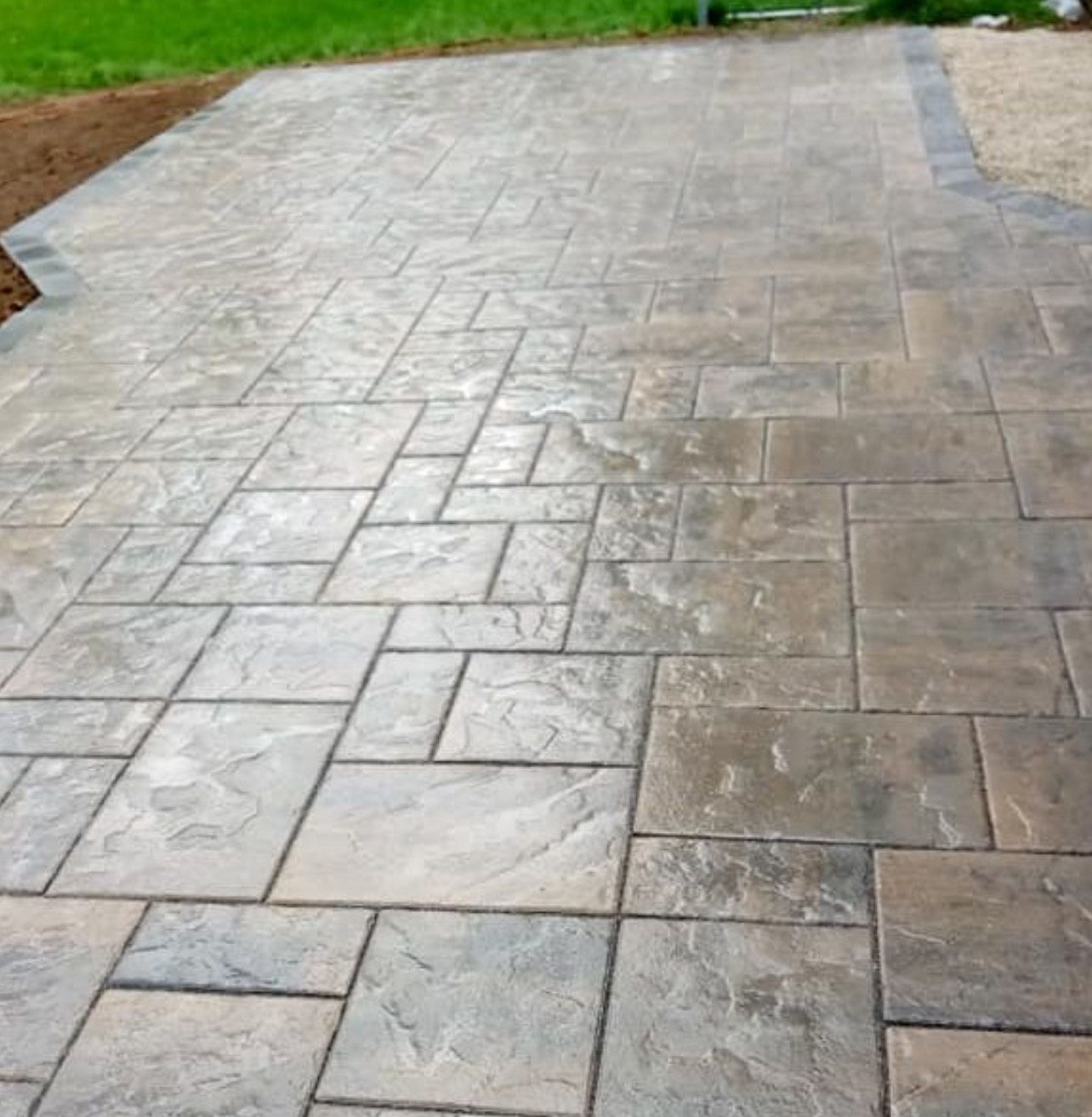 A brick walkway with a grassy area in the background