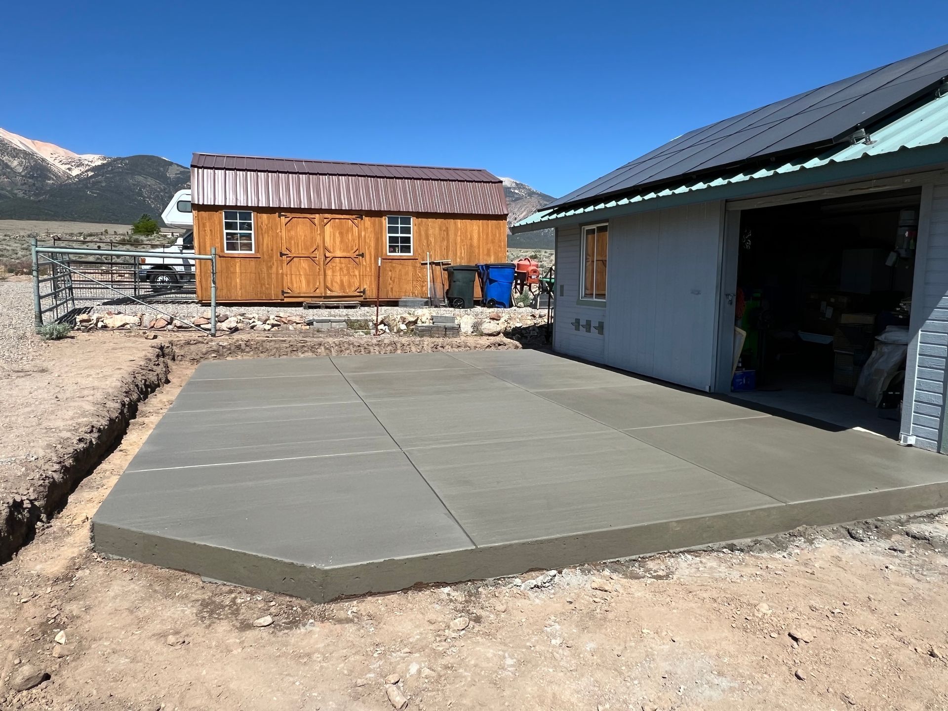A concrete patio is being built in front of a garage.