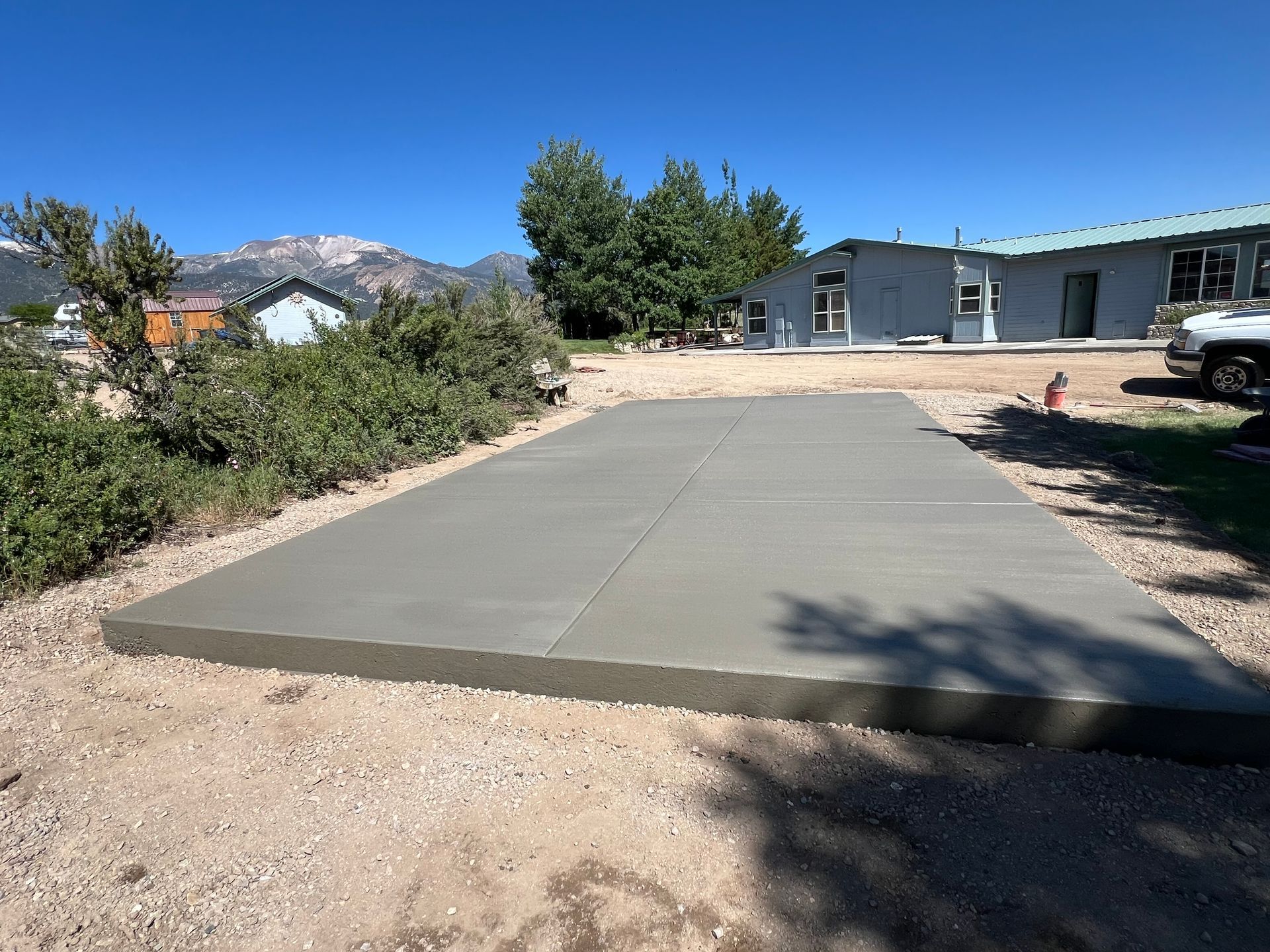 A large concrete slab is sitting in the dirt in front of a house.