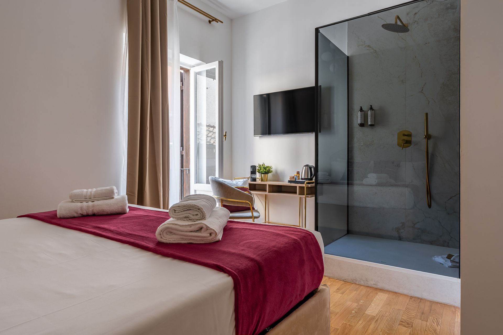 A hotel room with a king size bed and a walk in shower.