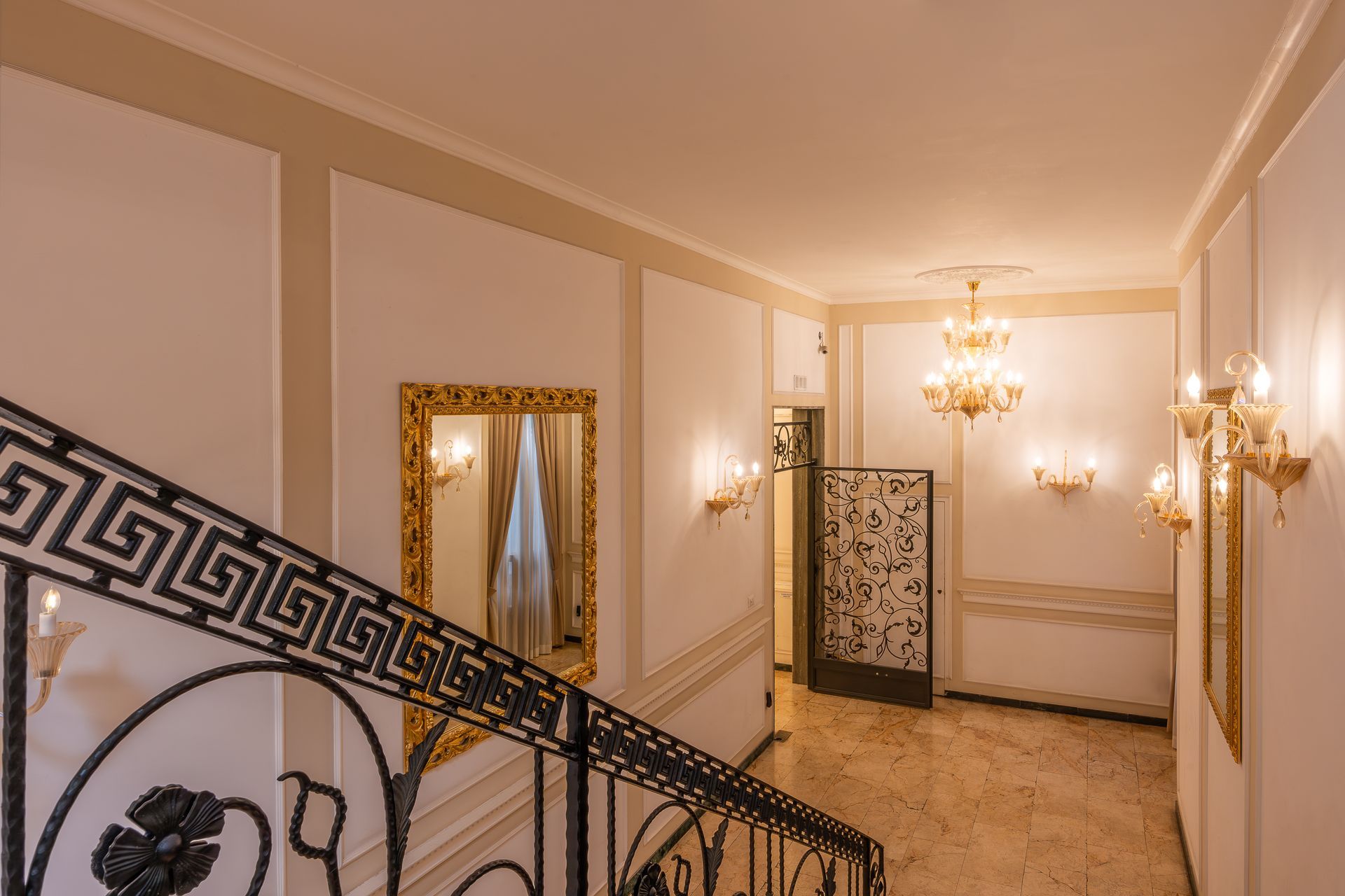 A staircase in a hallway with a wrought iron railing and a mirror.