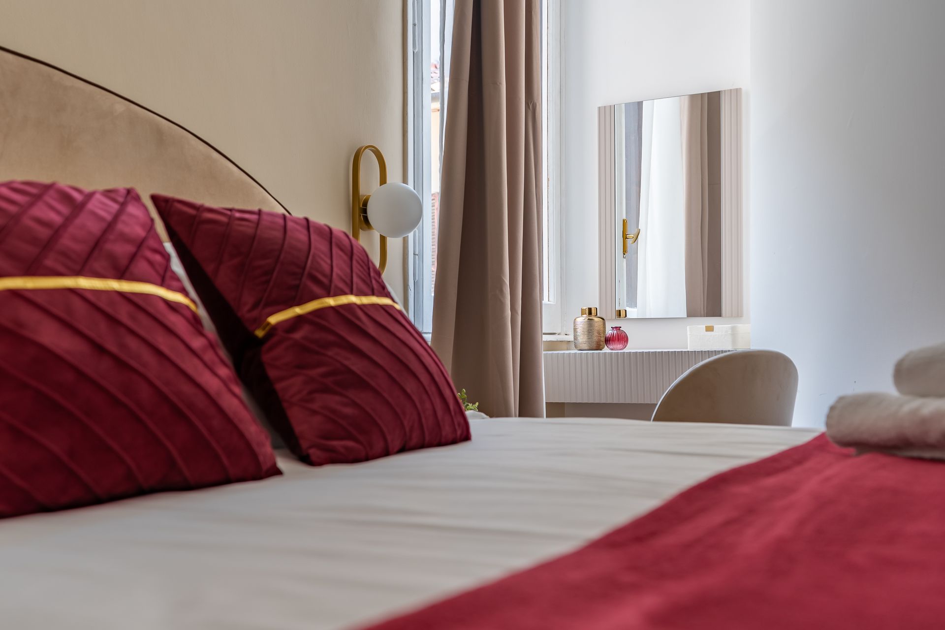A bed with red pillows and a red blanket in a hotel room.