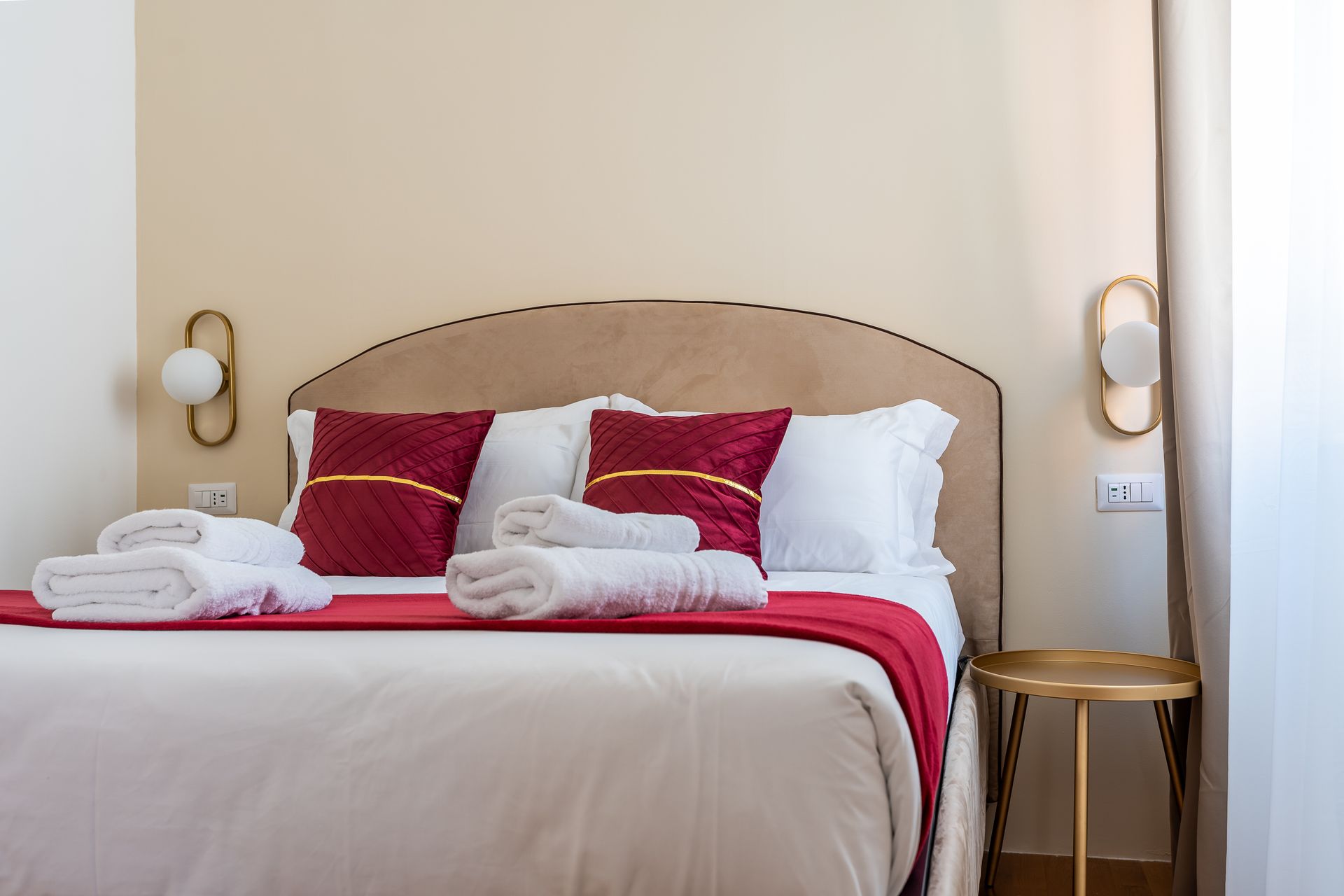 A bed with red pillows and white sheets in a hotel room.