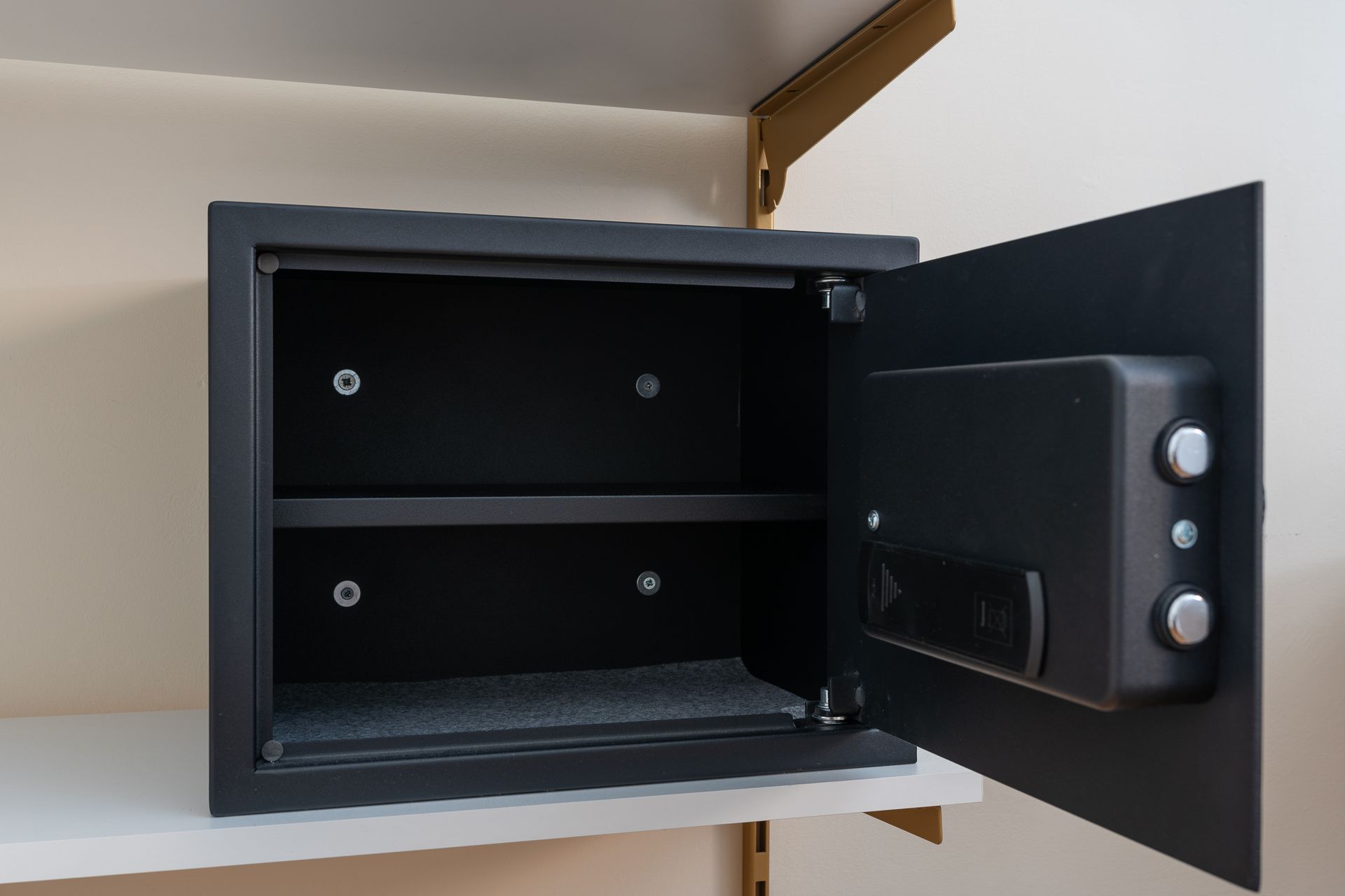 An open safe is sitting on a shelf with the door open.