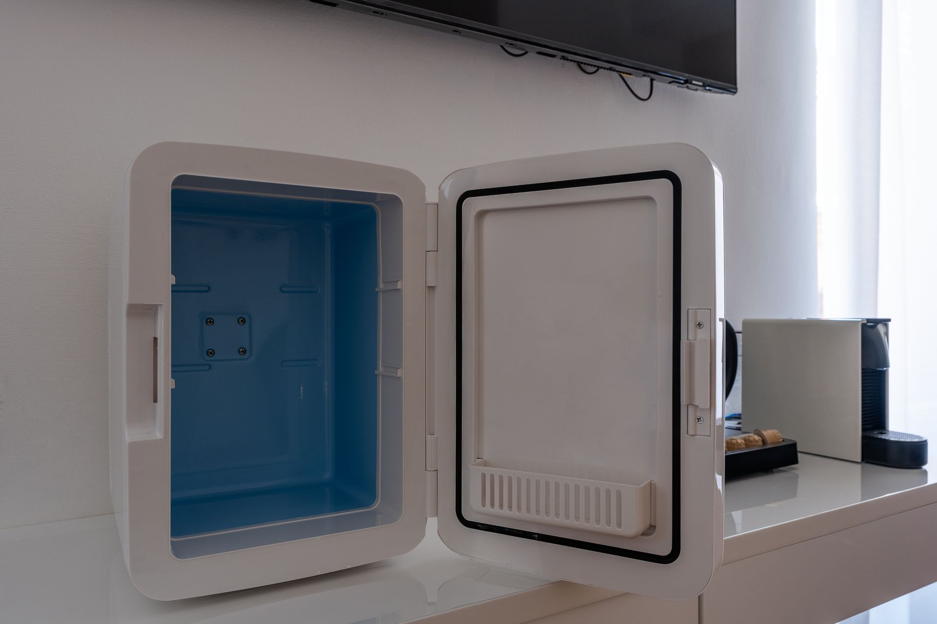 A small refrigerator with the door open is sitting on a table.