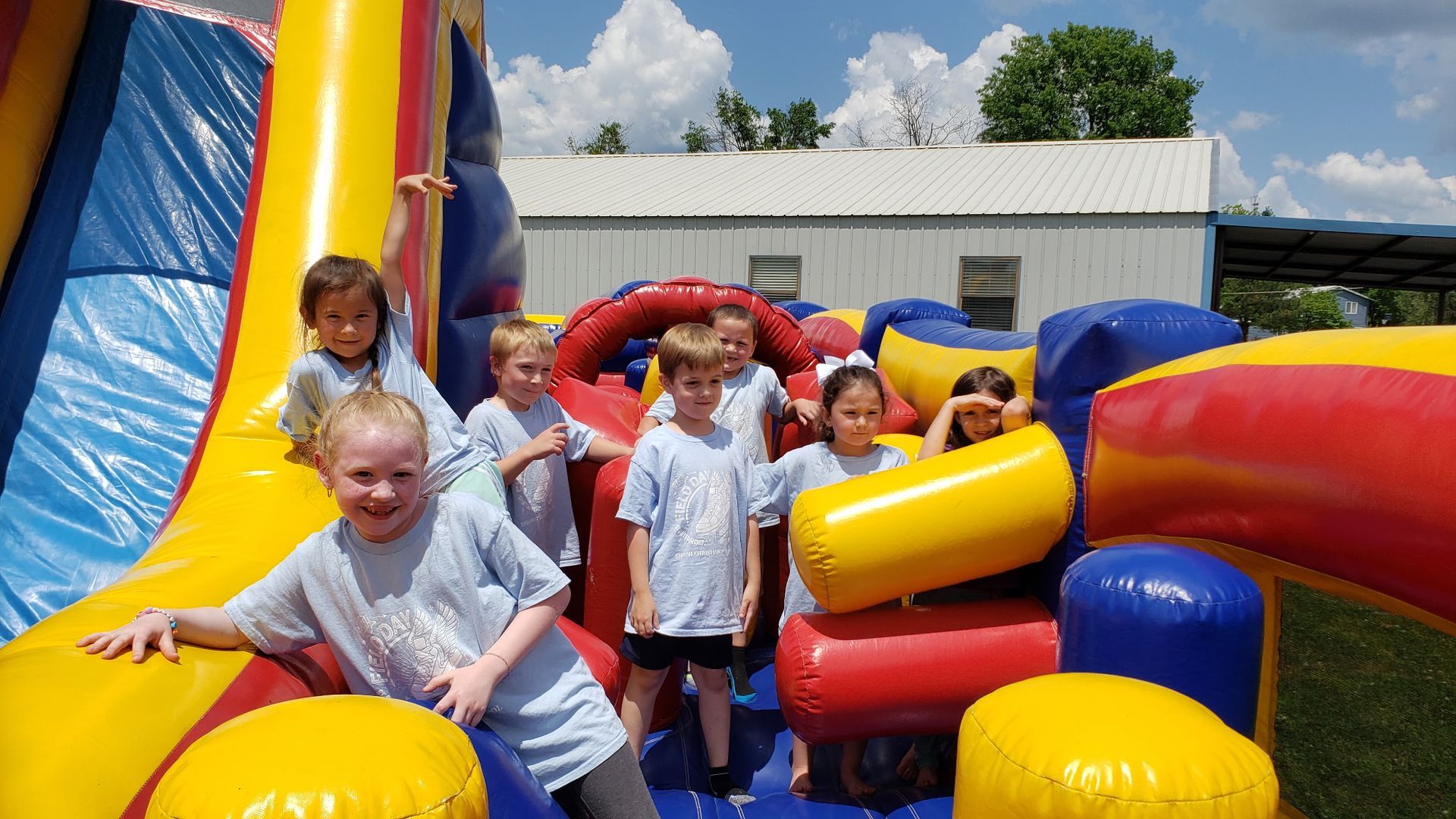 Children playing in a colorful inflatable obstacle course outdoors.