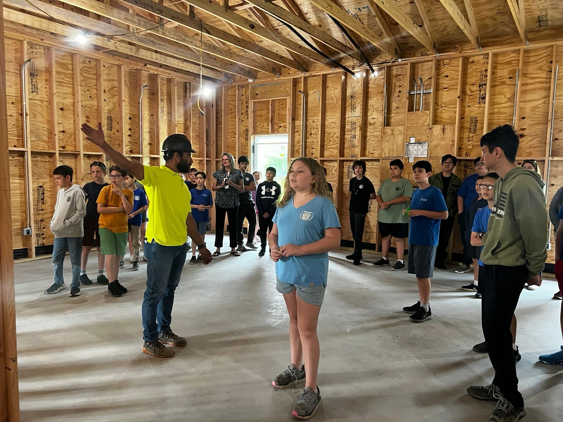 Group of people standing in a wooden-framed room, appearing to practice or rehearse indoors.