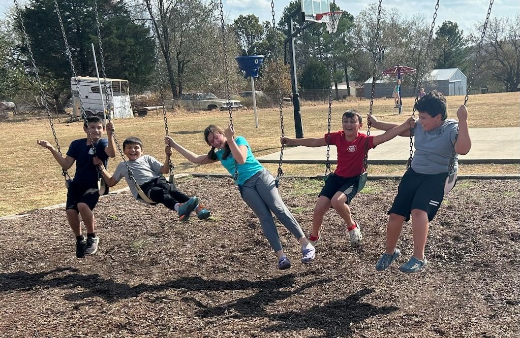 A group of children are playing on swings at a playground.