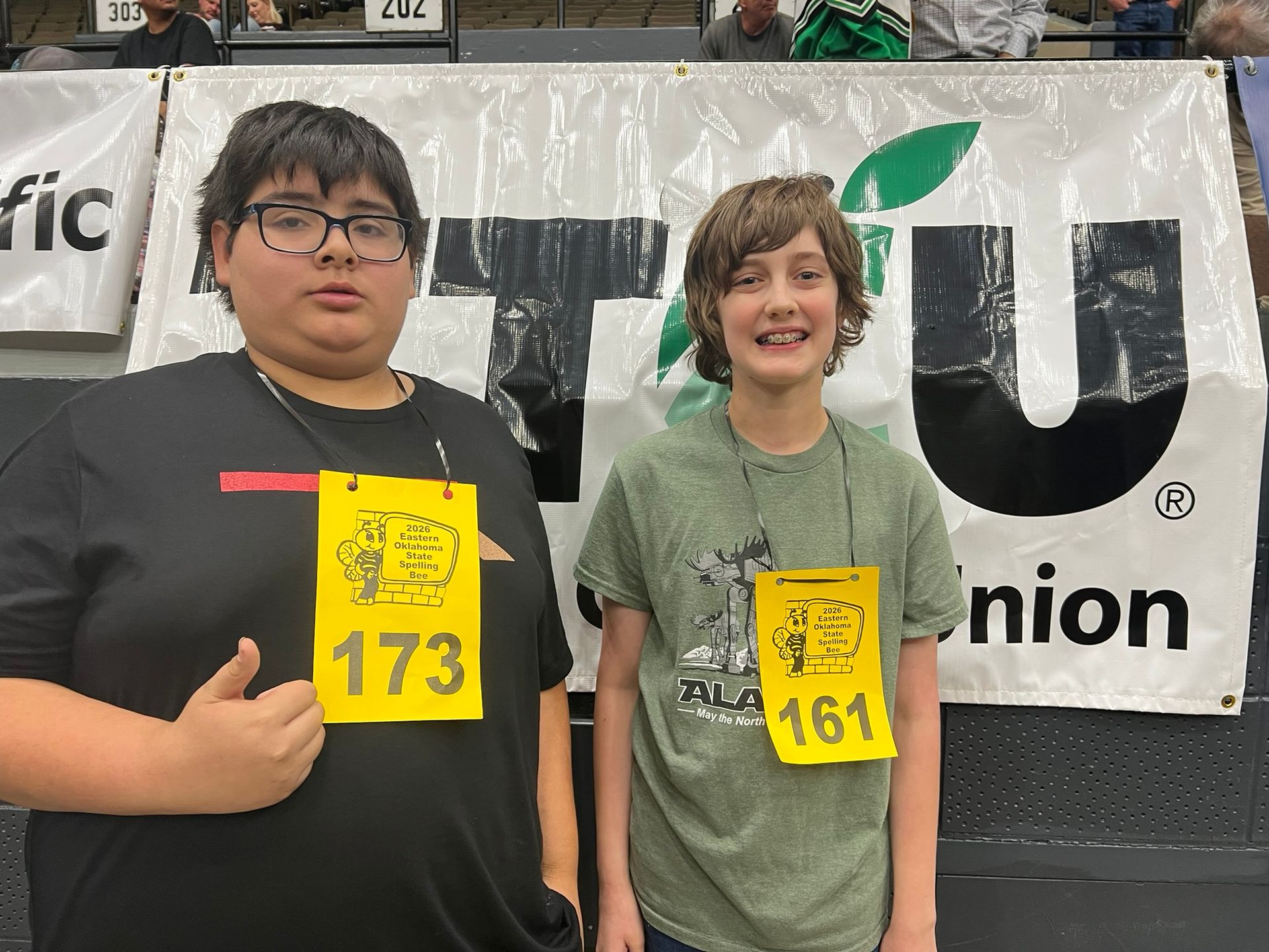 Two people wearing event bibs 173 and 164 posing indoors in front of a banner.