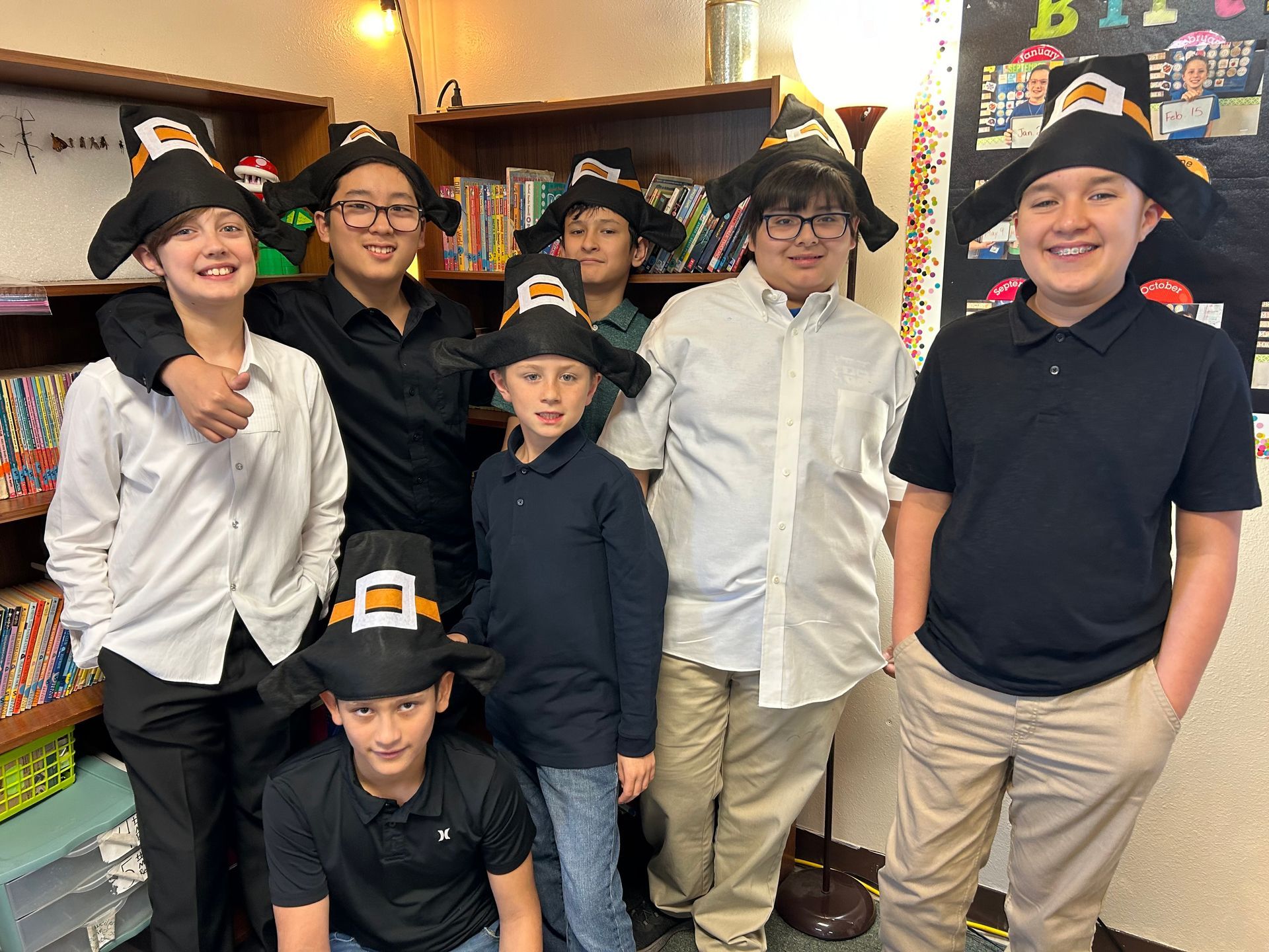 A group of young boys wearing pilgrim hats are posing for a picture.