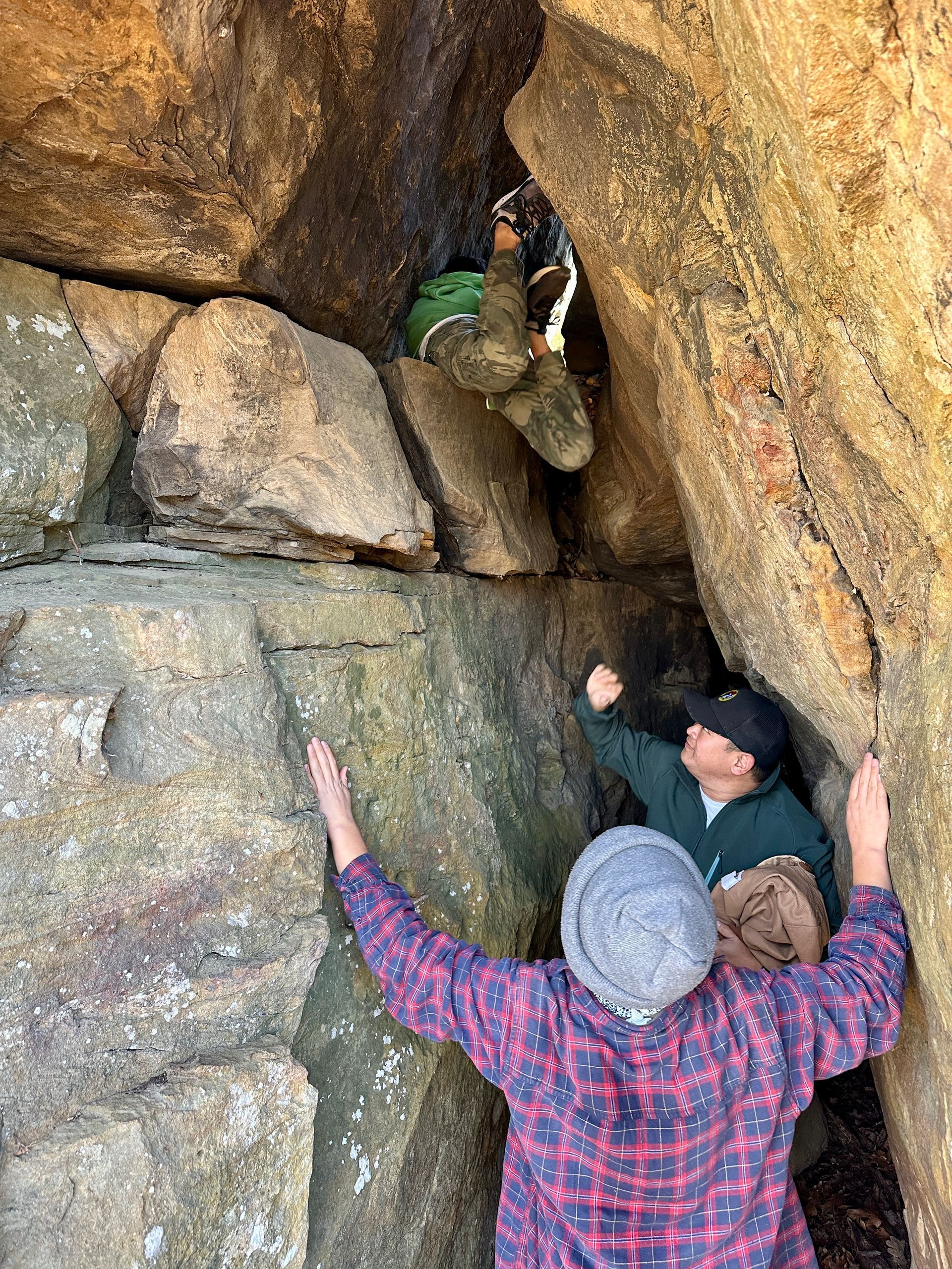 A group of people are climbing up a rock wall.
