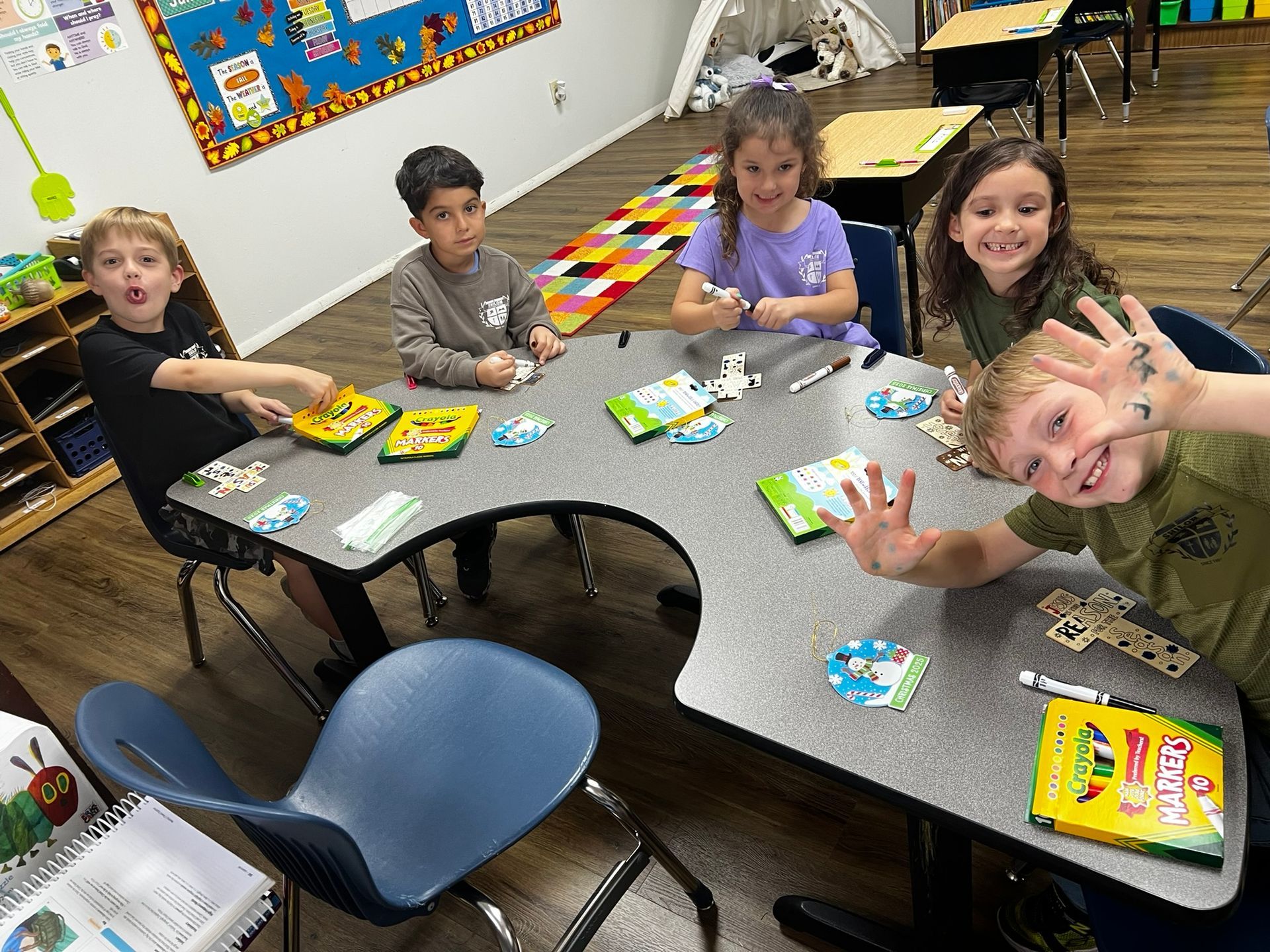 Children at a table playing games. Classroom setting. Colorful, cheerful expressions.