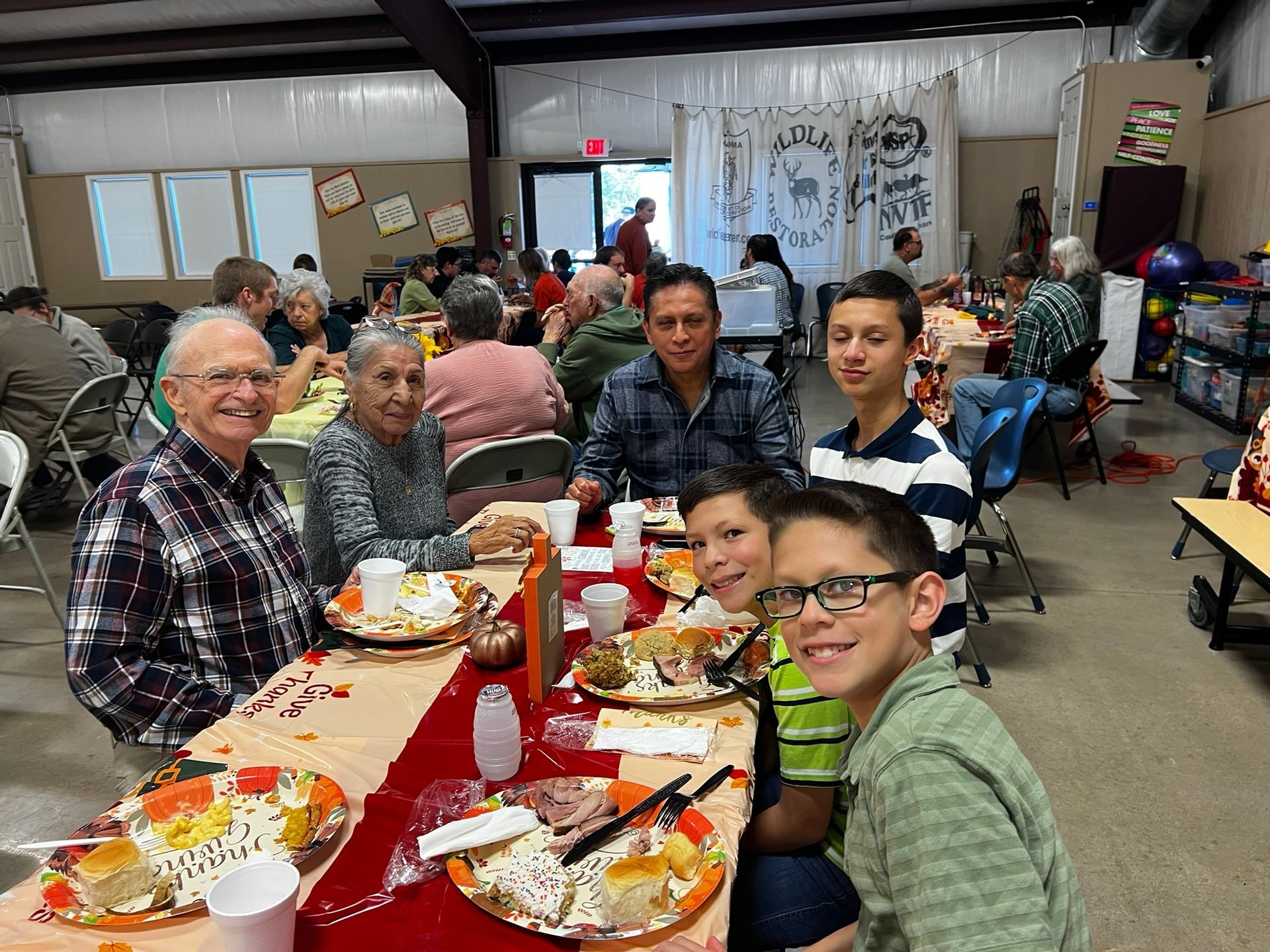 People seated at a Thanksgiving table, enjoying a meal indoors.