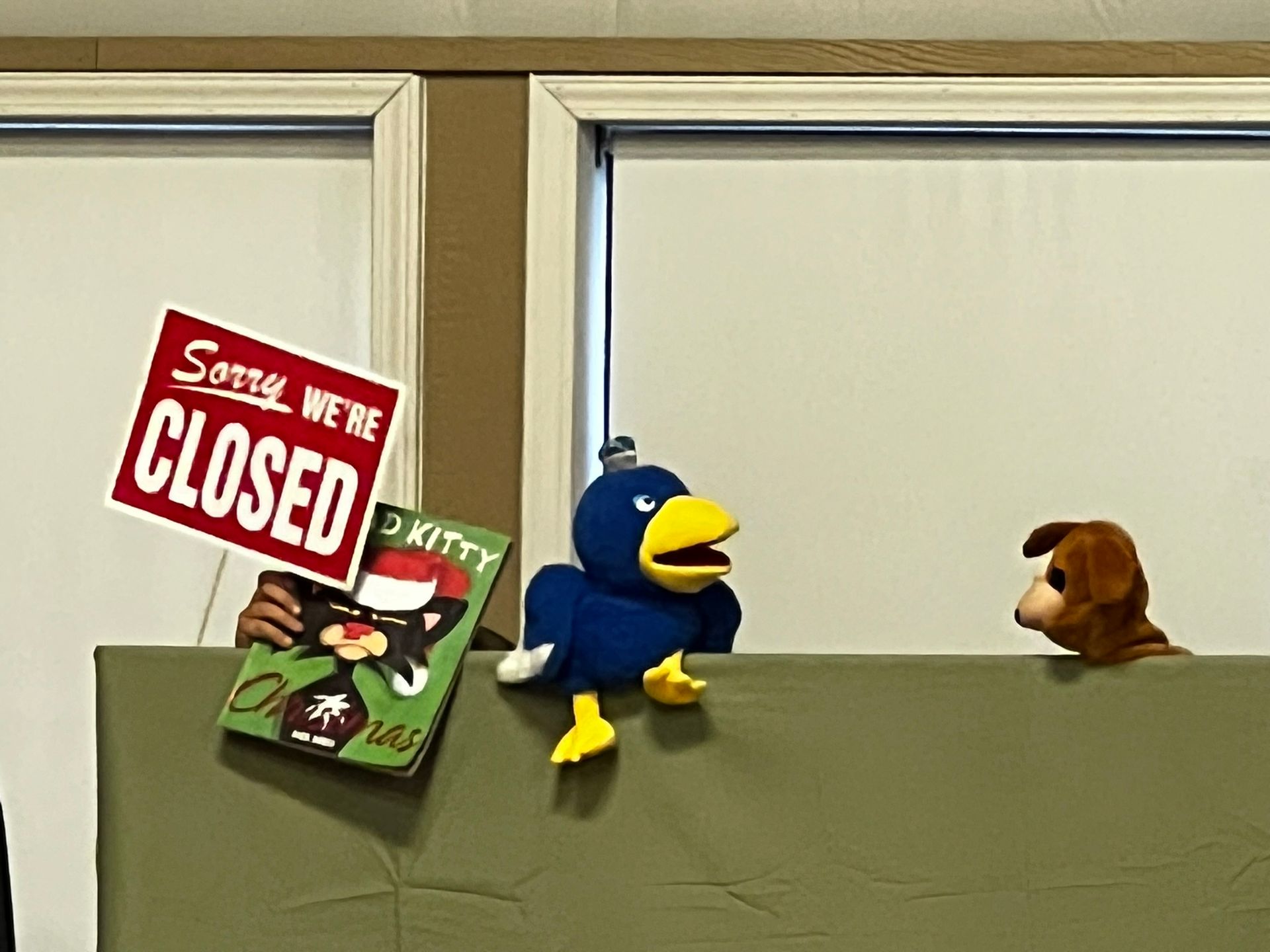A blue bird puppet, a dog puppet, and a sign that says 