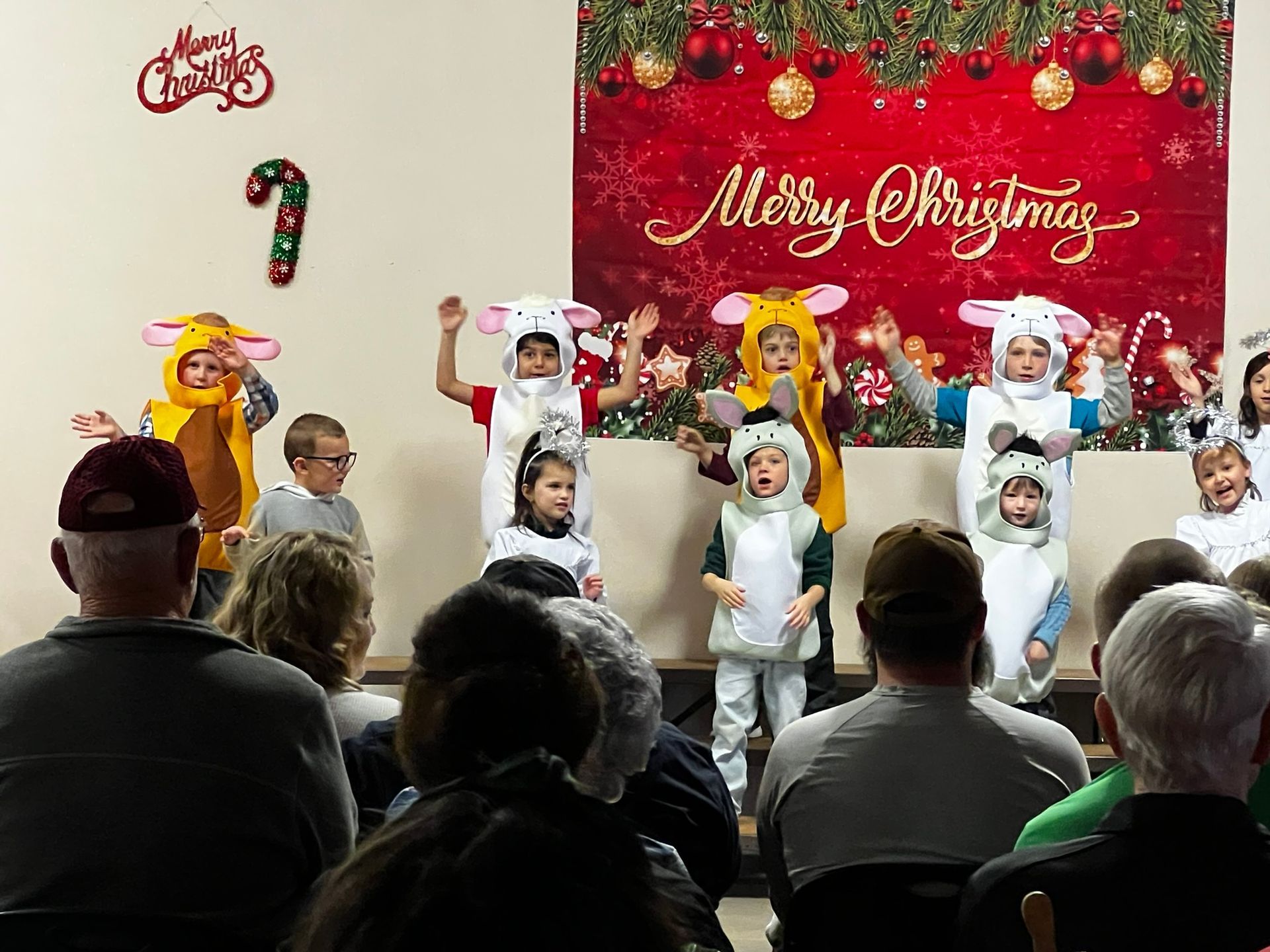 Children in sheep costumes perform onstage for an audience. A 