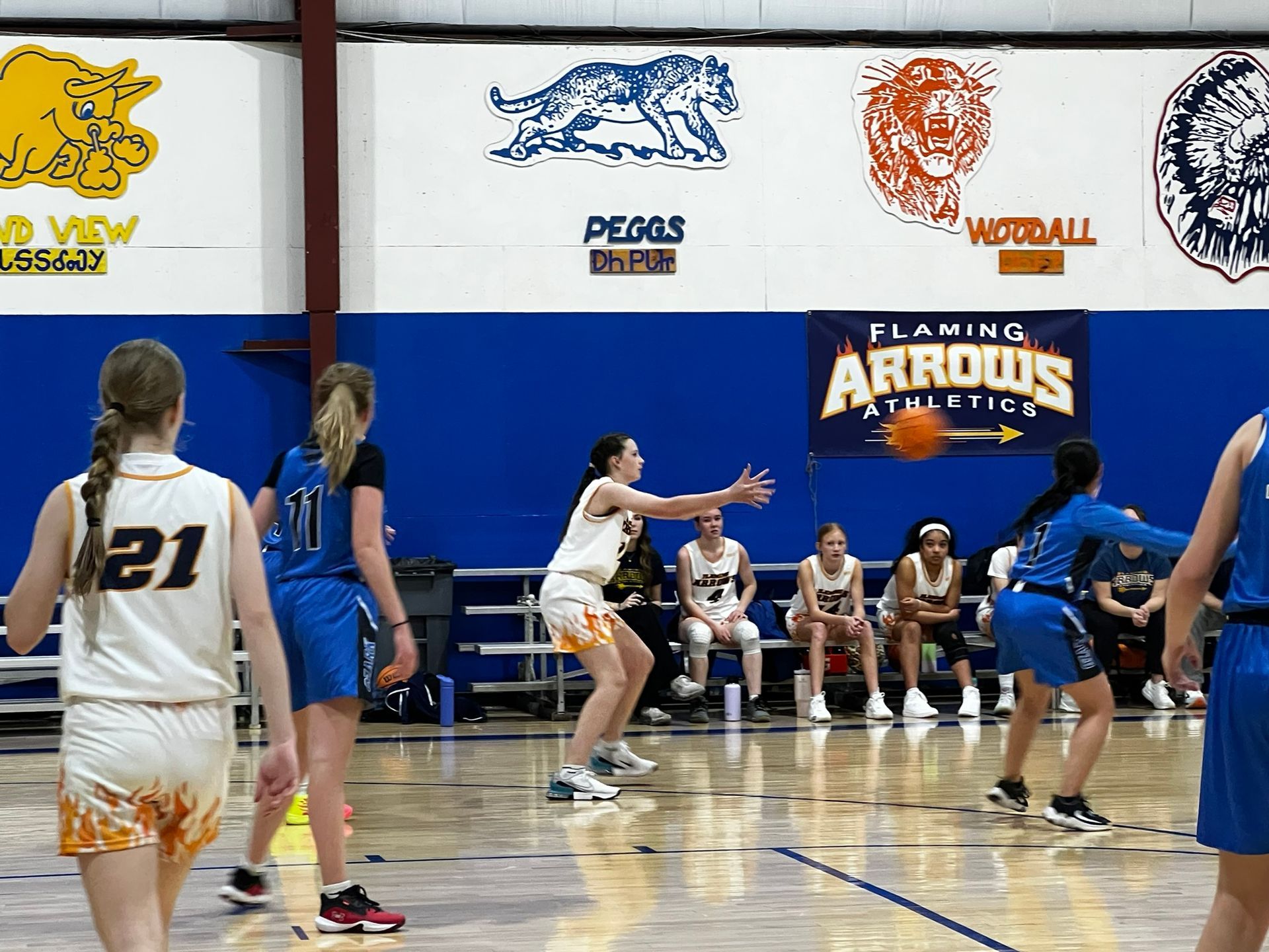 Basketball players in action on court. A player in a yellow jersey prepares to pass the ball.