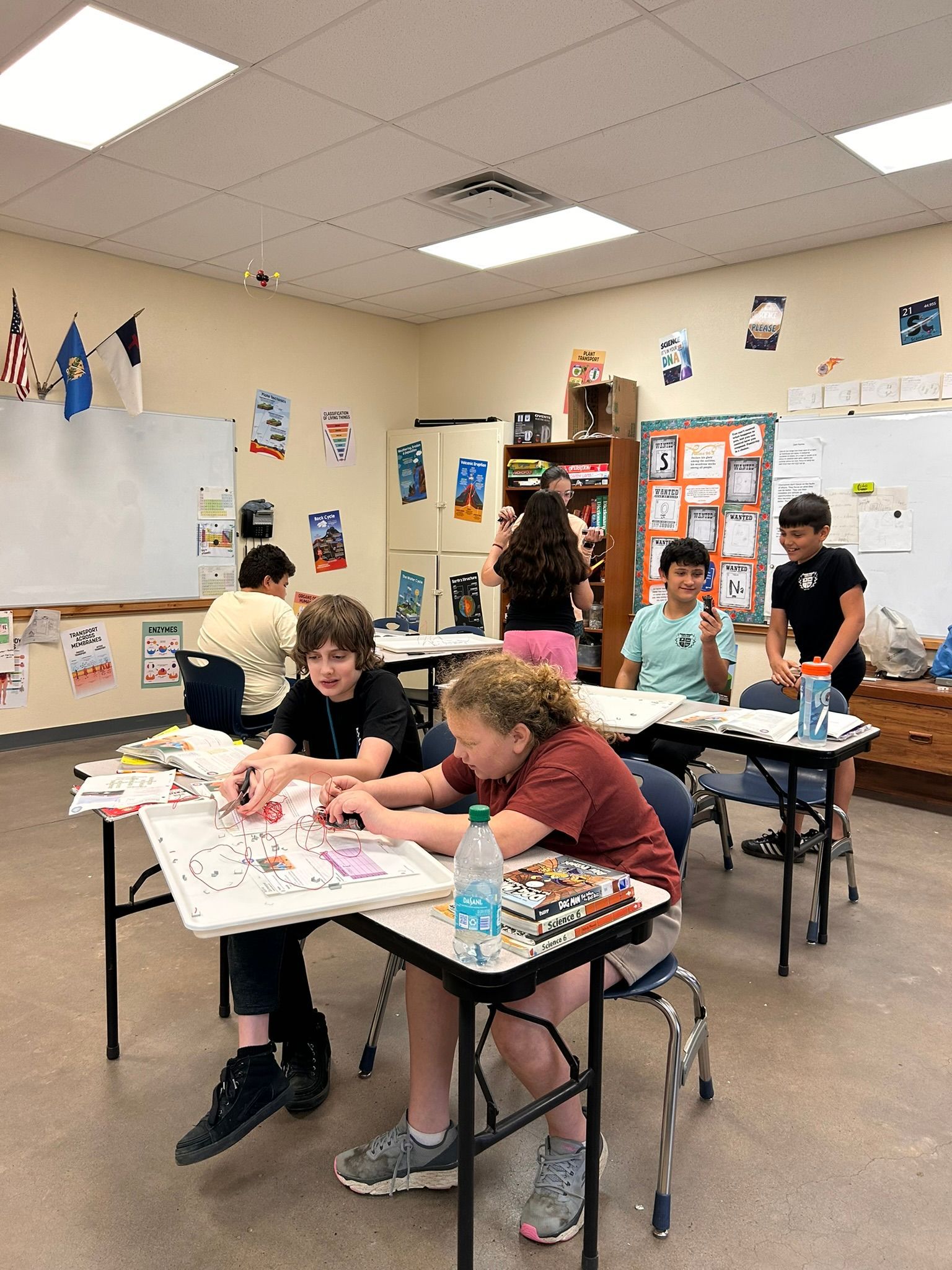 Students working at tables in a decorated classroom, focusing on a craft activity.