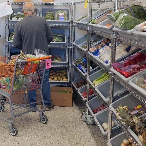 A man is pushing a shopping cart full of fruits and vegetables in Castle Rock Food Pantry