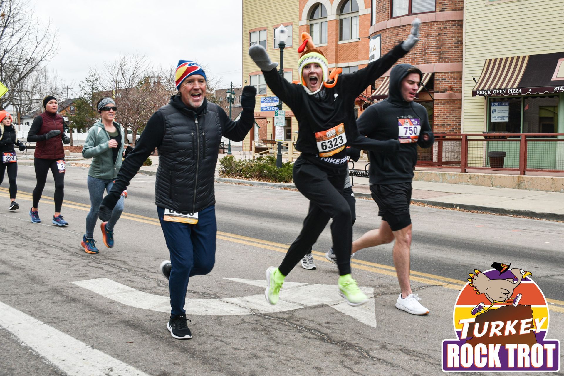 A group of people are running down a street in Castle Rock Turkey Rock Trot