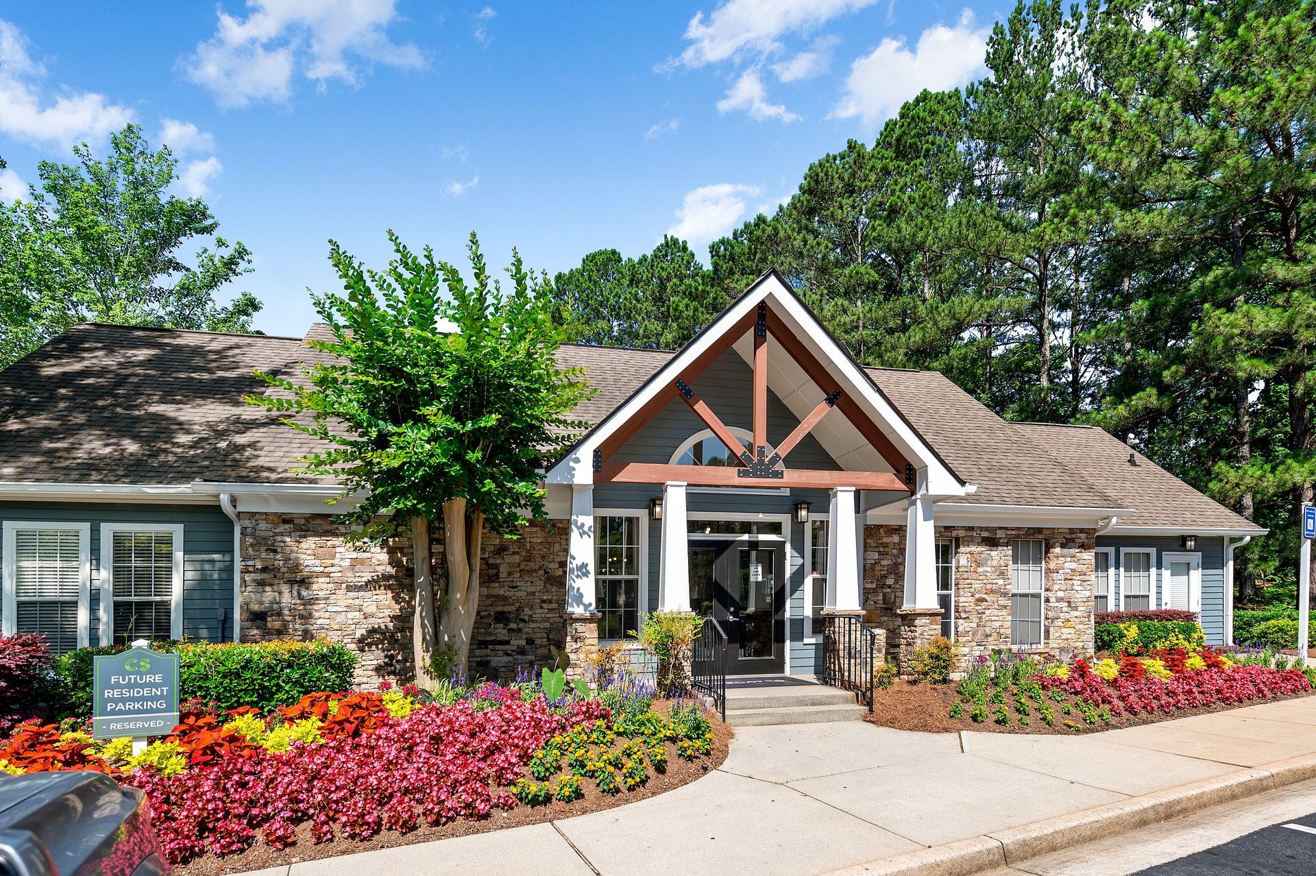 Apartment leasing office with colorful flowerbeds and a blue exterior at Creekside at White Oak in Newnan, GA.