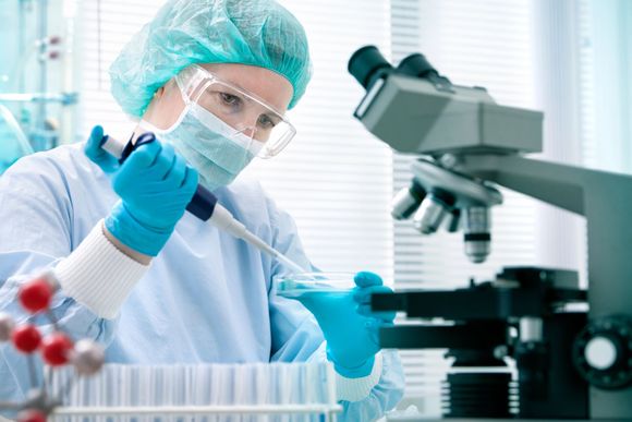 Un científico está trabajando en un laboratorio con una pipeta y un microscopio.