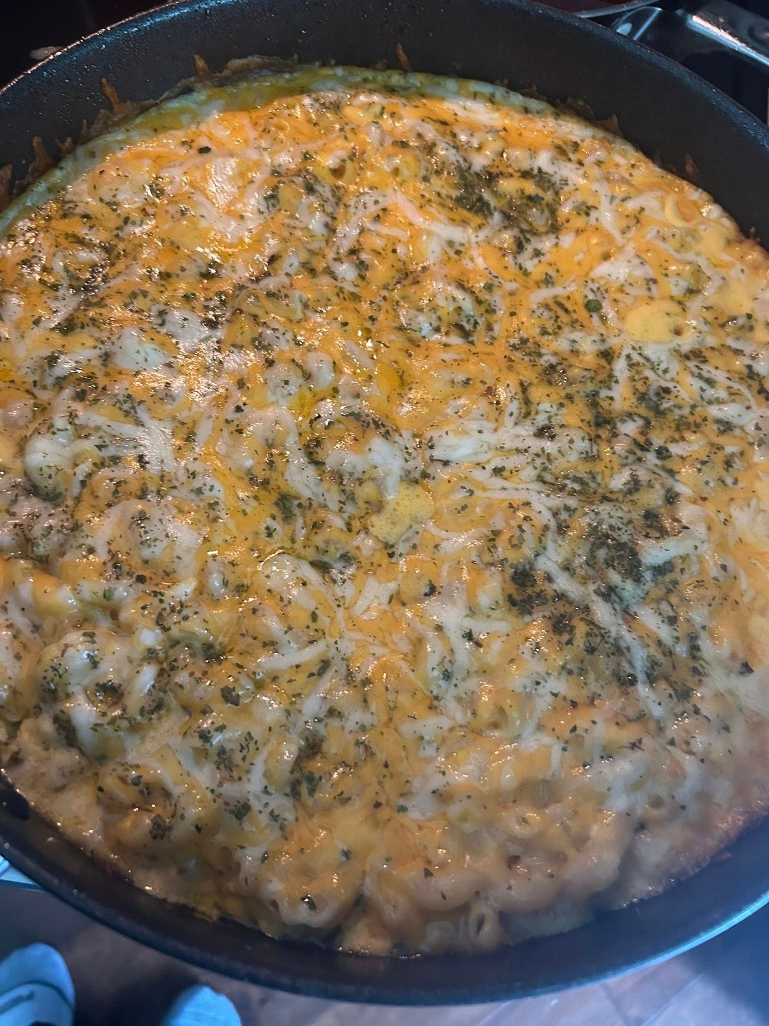 A pan filled with macaroni and cheese is sitting on a stove.