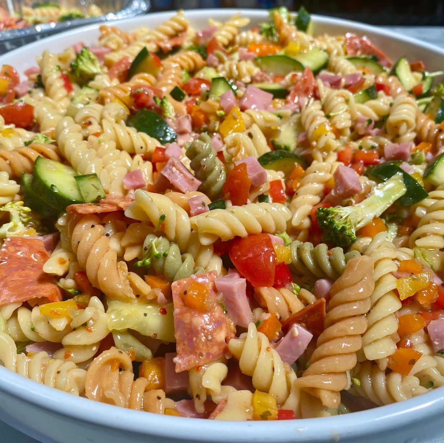 A pasta salad with vegetables and meat in a white bowl