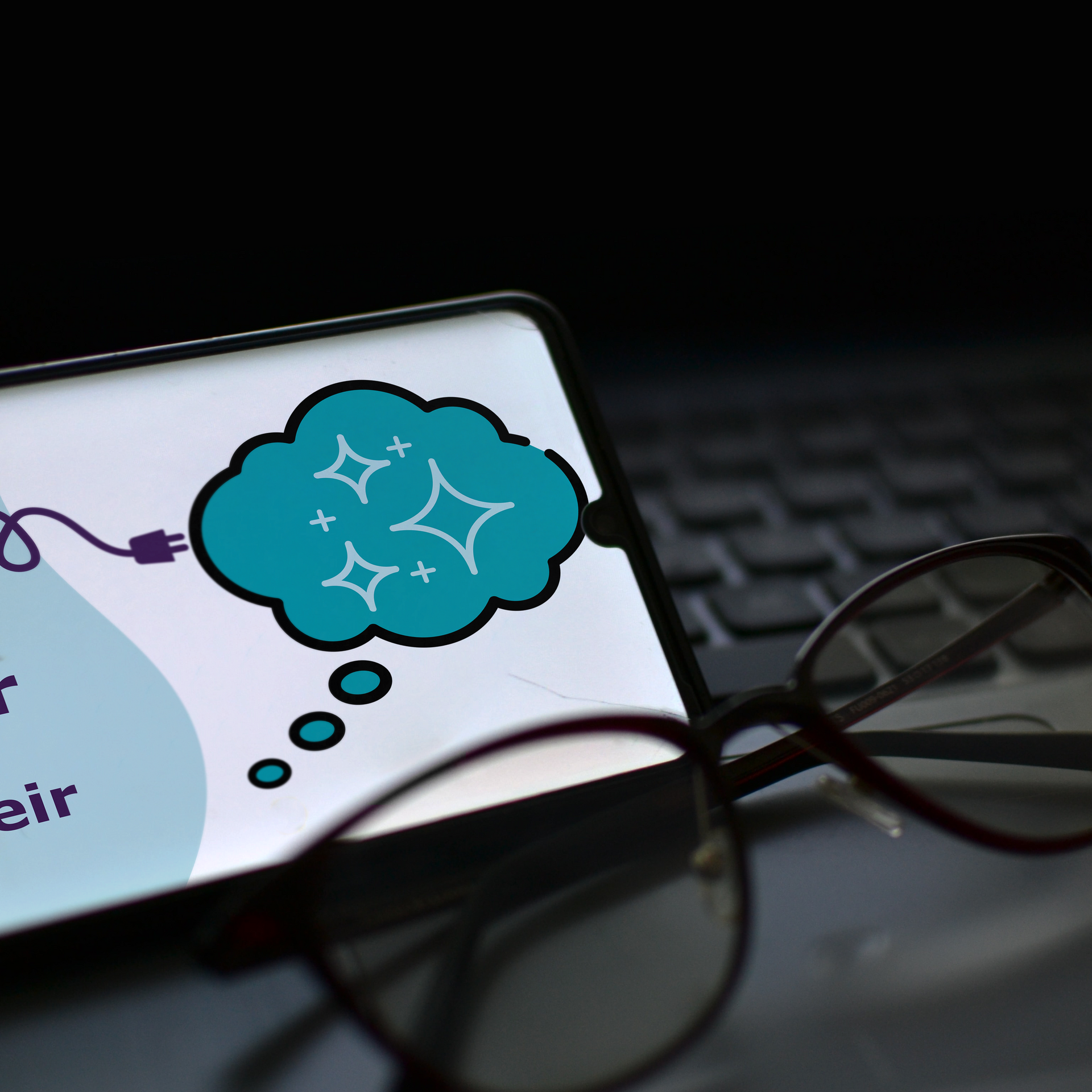 A pair of glasses sits next to a cell phone with a thought bubble on the screen