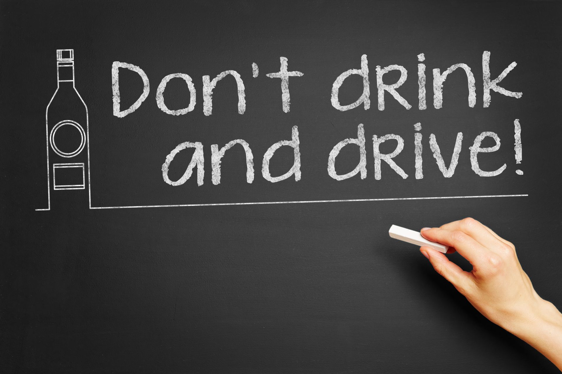 A hand holds a piece of chalk writing