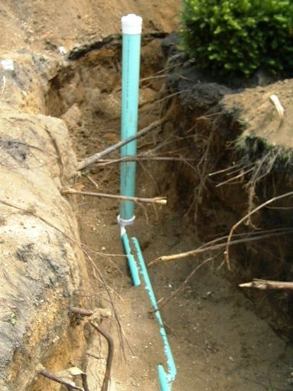 A blue pipe is in a hole in the ground