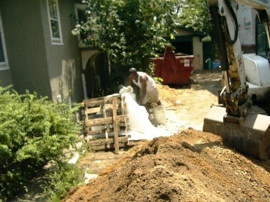 A man is working on a pile of dirt in front of a house.