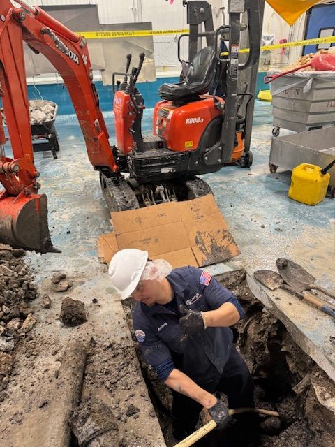 A man wearing a hard hat is digging a hole in the ground