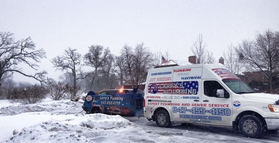 A white van is parked next to a blue truck in the snow.