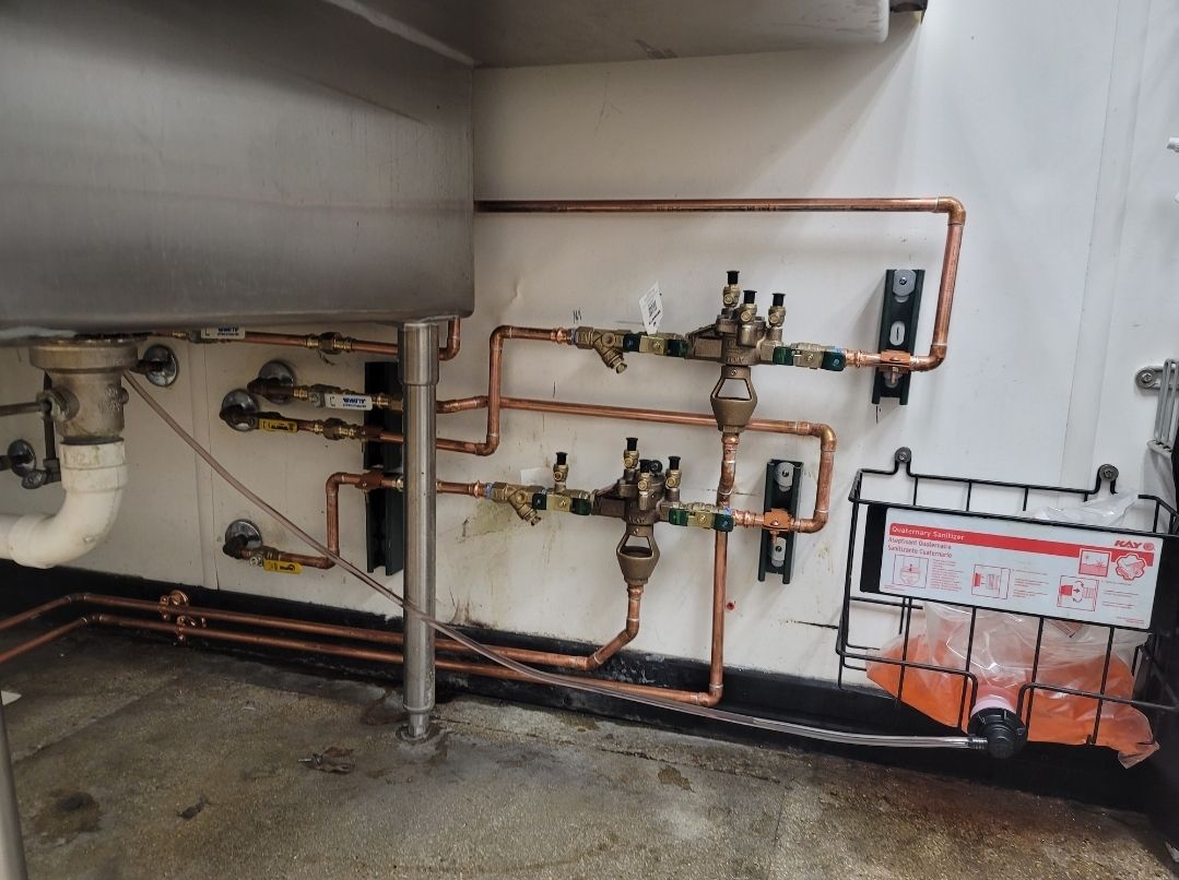 Copper pipes are connected to a sink in a kitchen.