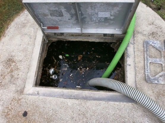 A green hose is coming out of a manhole cover