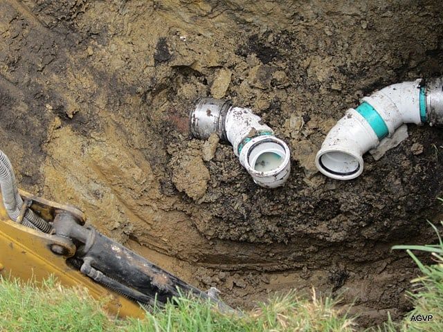 A couple of pipes are laying in the dirt next to a bulldozer.