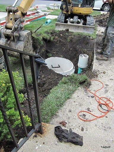 A man is digging a hole in the ground to install a septic tank.
