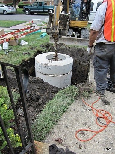 A man in an orange vest is digging a hole in the ground.