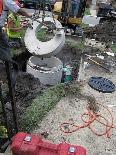 A man is lifting a concrete ring into a hole in the ground.