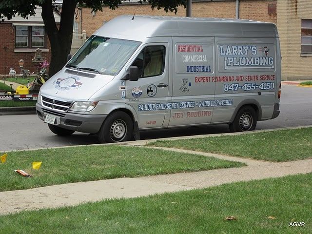A larry 's plumbing van is parked on the side of the road