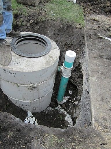 A man is digging a hole in the ground to install a septic tank.