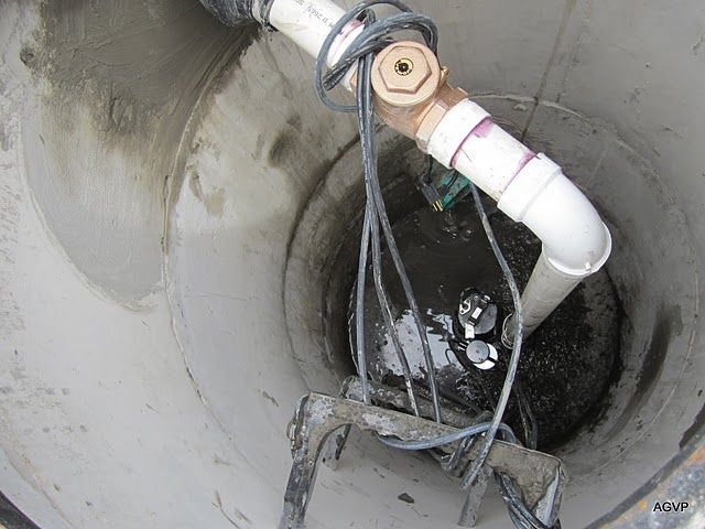 A manhole cover with pipes and wires coming out of it.