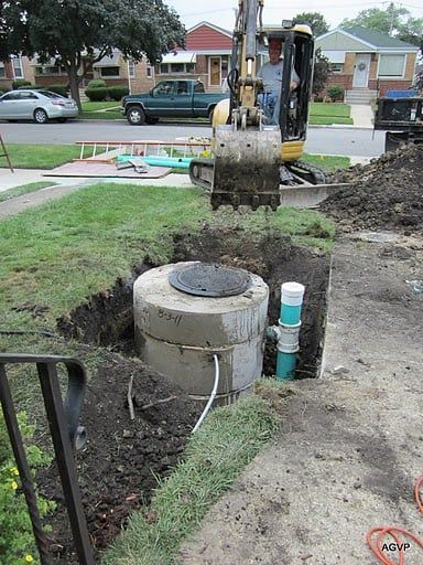 A man is digging a hole in the ground to install a septic tank.