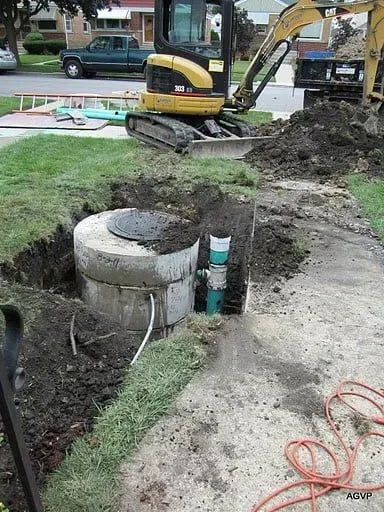 An excavator is digging a hole in the ground next to a manhole cover.